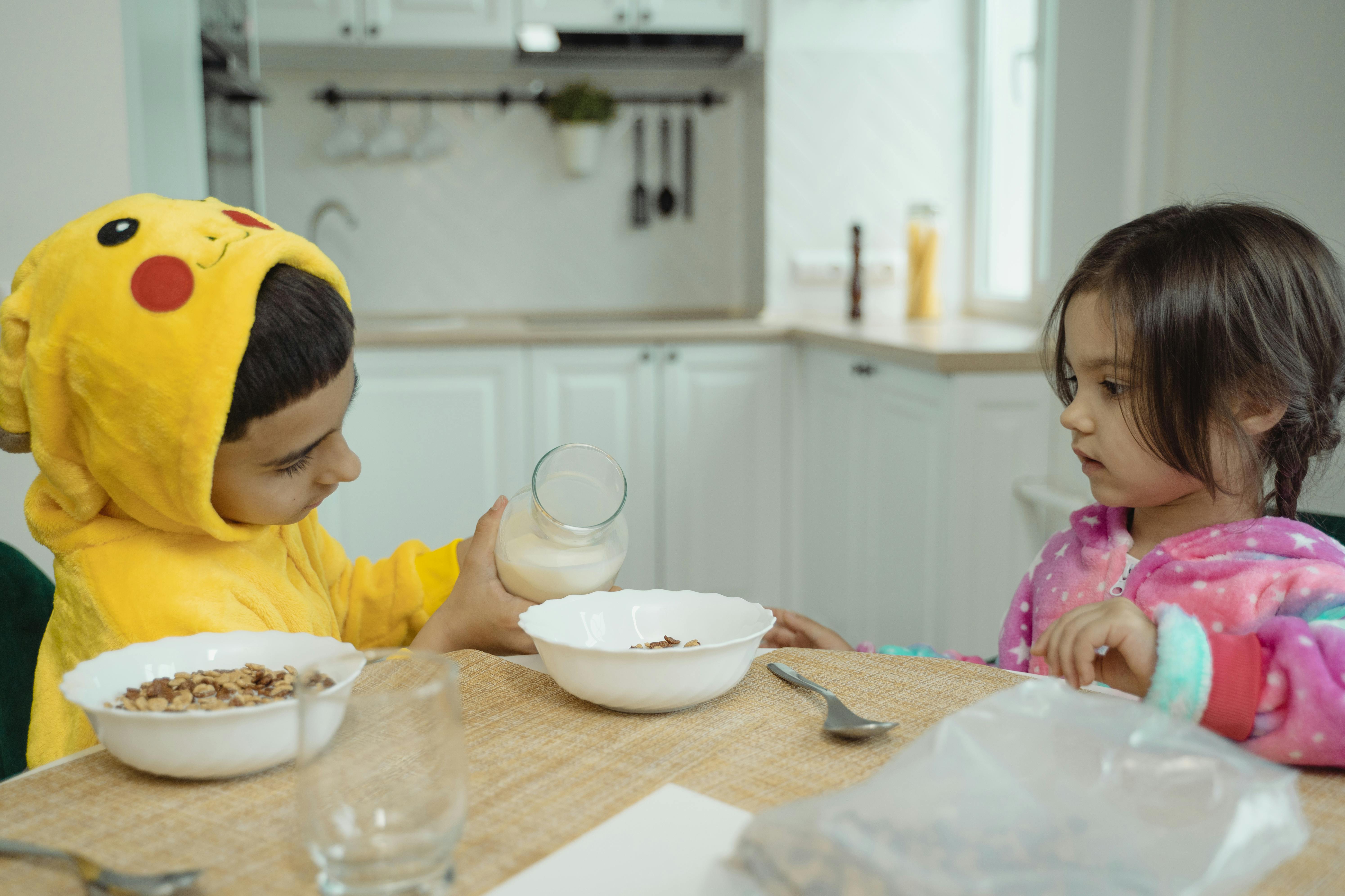 Young children eating cereal together during free breakfast in schools morning provision